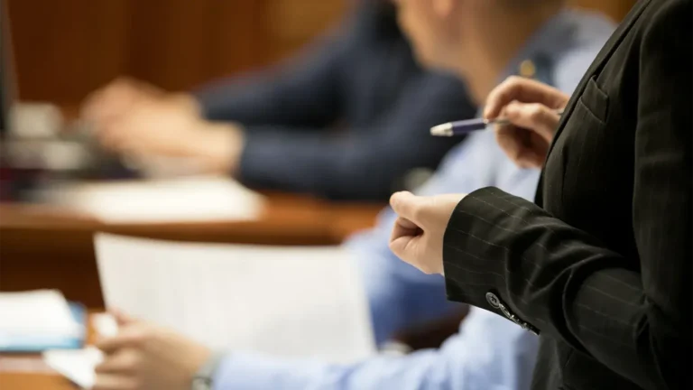 Felony defense lawyer torso pictured in a courtroom with other people in a blurry background